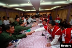 FILE - Representatives from Myanmar's government and the Karen National Union (KNU) shake hands during peace talks at Hotel Zwekabin in Pa-an, capital of the Karen State in eastern Myanmar, Jan. 12, 2012.