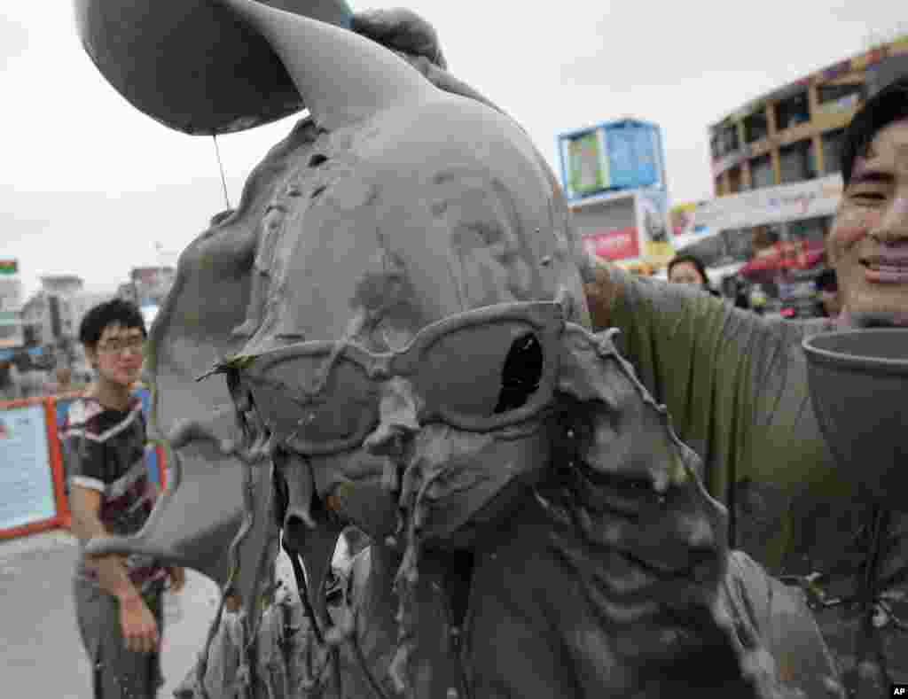 Một người đàn ông đổ nước bùn lên đầu của bạn gái của mình trong Lễ hội bùn Boryeong tại bãi biển Daecheon ở Boryeong, Hàn Quốc. Lễ hội bùn hàng năm gồm có đấu vật bùn và trượt bùn. 
