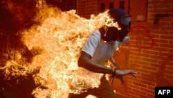 Esta foto de un manifestante venezolano envuelto en llamas durante enfrentamientos con la policía anti disturbios en Caracas, Venezuela, el 3 de mayo de 2017, le valió una nominación para Foto del Año de World Press Photo a Ronaldo Schemidt de AFP.