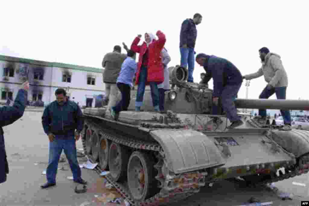 Residents stand on a tank inside a security forces compound in Benghazi, Libya on Monday, Feb. 21, 2011. Libyan protesters celebrated in the streets of Benghazi on Monday, claiming control of the country's second largest city after bloody fighting, and an