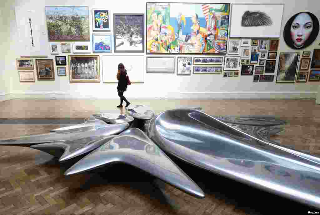 FILE - A woman looks at paintings behind a sculpture by Zaha Hadid titled 'Kloris' during the media preview of the Summer Exhibition at the Royal Academy of Arts in central London, England, June 5, 2013.
