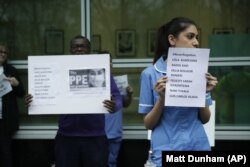 Hospital workers hold placards with the names of their colleagues who have died from coronavirus as they take part in a protest calling on the British government to provide PPE (personal protective equipment) across Britain.