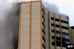 People trapped by an intense fire that burst in the building of the Ministry of Finance in San Salvador, July 7, 2017, stand on the top of the tower.