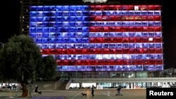 People walk by as the municipality building in Tel Aviv is lighted in the colors of the American flag in solidarity with the victims of the Pittsburgh, Pa., synagogue attack, Oct. 27, 2018.