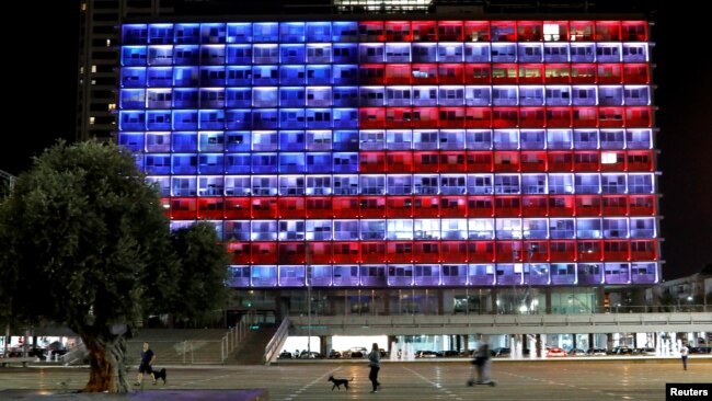 People walk by as the municipality building in Tel Aviv is lighted in the colors of the American flag in solidarity with the victims of the Pittsburgh, Pa., synagogue attack, Oct. 27, 2018.