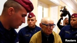 Former Communist Party official Bela Biszku is escorted by police during his trial in Budapest on May 13, 2014.