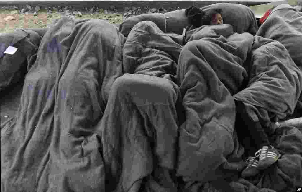 Para migran tidur di jalur kereta api dekat sebuah kamp pengungsi sementara di Idomeni, Yunani.
