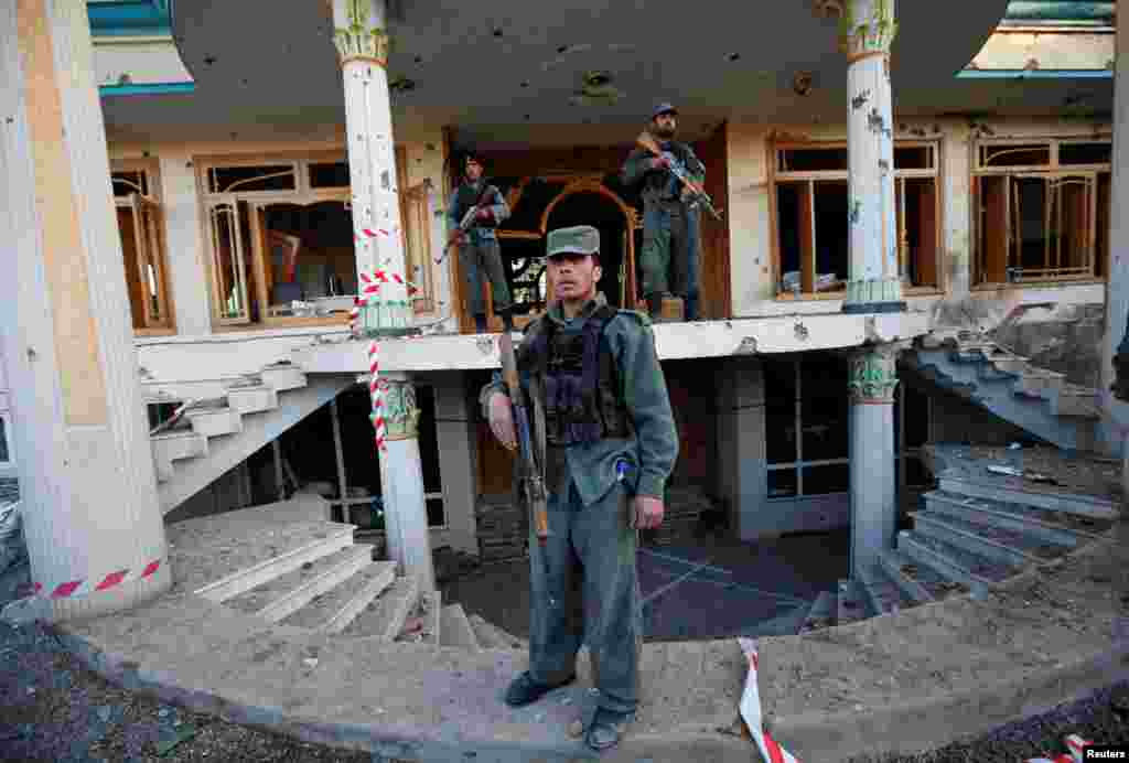 Afghan policemen stand guard at an election commission office after an attack by suicide bombers and gunmen in Kabul.
