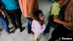 FILE - Women and their children wait in line to register at the Honduran Center for Returned Migrants after being deported from Mexico, in San Pedro Sula, northern Honduras June 20, 2014.