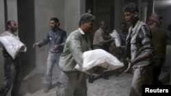 Men store bags of flour unloaded from a Red Crescent aid convoy in the rebel held besieged town of Jesreen, in the eastern Damascus suburb of Ghouta, Syria, March 7, 2016. 
