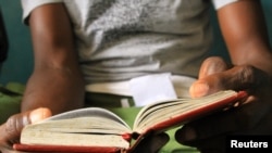 Recovering heroin addict reads his Narcotics Anonymous book at Defence Drugs Women Organisation, Mombasa, Kenya, July 20, 2012. (Jill Craig/VOA)