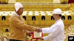 Presiden Htin Kyaw (kiri) menerima tanda kepresidenan dari mantan Presiden Thein Sein, dalam serah terima jabatan Presiden Myanmar di Naypyitaw (30/3).