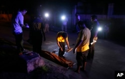 Funeral workers prepare to remove the body of a crime suspect after he was killed in gunbattles, Aug. 17, 2017 in Manila, Philippines.