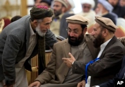 FILE - Afghanistan's former PM Ahmad Shah Ahamdzai, right, talks with an Afghan delegate as Ghairat Baheer, center, head of political cell Hizb-e-Islami Afghanistan listens during a conference title 'Peace and Reconciliation in Afghanistan', in Islamabad.