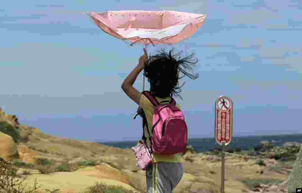 A girl struggles with winds from approaching Typhoon Matmo along the eastern coast of Keelung, northeastern Taiwan.