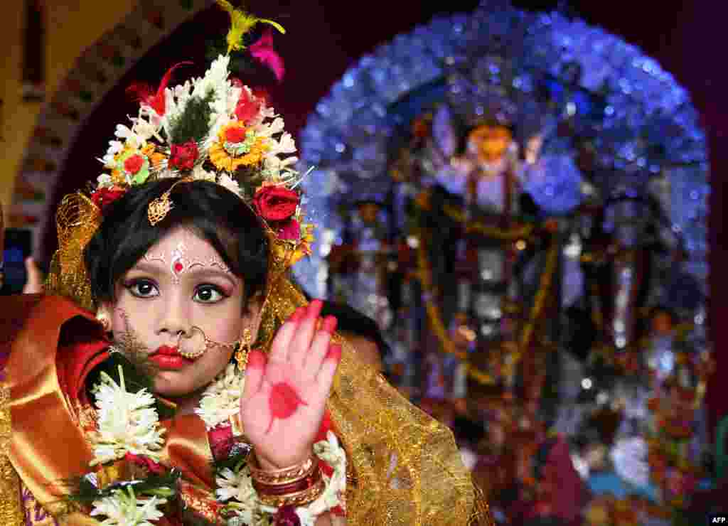 An Indian priest worships six-year-old Hindu girl Anushka Chetterjee (C) dressed as the Hindu goddess Durga at a 'pandal' for the celebrations of the 'Durga Puja' festival in Kolkata.