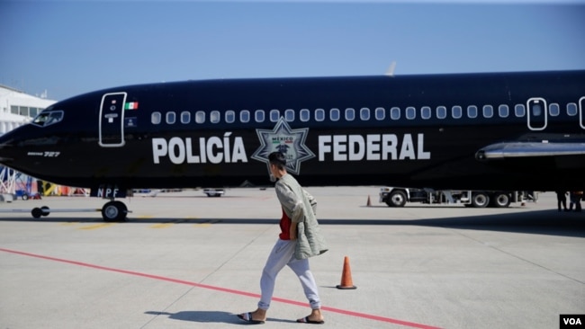 Migrante hondureño camina frente al avión mexicano que lo devolció a su país.