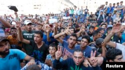 Migrantes muestran sus pasajes de tren frente a la principal estación de trenes en Budapest, Hungría, el martes, 1 de septiembre de 2015. 