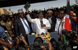 FILE - Opposition leader Raila Odinga (C) accompanied by lawyers Miguna Miguna (C-L), Tom "T.J." Kajwang, (C-R) and politician James Orengo (R) holds a bible aloft after swearing an oath during a mock "swearing-in" ceremony at Uhuru Park in downtown Nairobi.