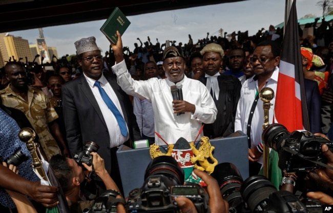 FILE - Opposition leader Raila Odinga (C) accompanied by lawyers Miguna Miguna (C-L), Tom "T.J." Kajwang, (C-R) and politician James Orengo (R) holds a bible aloft after swearing an oath during a mock "swearing-in" ceremony at Uhuru Park in downtown Nairobi, Kenya, Jan. 30, 2018.