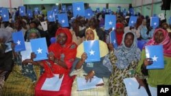 Somalia's constituency assembly members hold up copies of the proposed new constitution during the beginning of a nine-day meeting in Mogadishu, July 25, 2012.