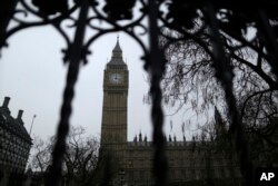 FILE - The Houses of Parliament and Elizabeth Tower, containing the bell know as Big Ben, are seen through a perimeter fence in London, Feb. 8, 2017. Lawmakers on the House of Commons' international development committee released a report Tuesday warning of endemic sexual exploitation across the international aid sector.