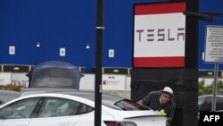 Seorang karyawan Tesla membersihkan sebuah mobil di showroom Tesla di Burbank, California, 24 Maret 2020. (Foto: AFP)