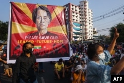FILE - A banner featuring Aung San Suu Kyi is displayed as protesters take part in a demonstration against the military coup in front of the National League for Democracy (NLD) office in Yangon, Feb. 15, 2021.