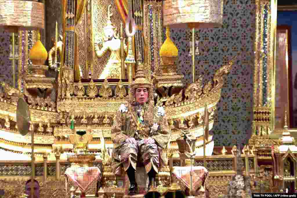 This screengrab from Thai TV Pool video taken on May 4, 2019 shows Thailand's King Maha Vajiralongkorn facing the audience wearing the gold crown while sitting on the throne during his coronation at the Grand Palace in Bangkok.