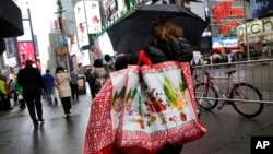 FILE - A woman walks through Times Square with holiday shopping bags, in New York, Dec. 2, 2015.