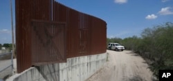 In this Aug. 11, 2017, file photo, a U.S. Customs and Border Patrol vehicle passes along a section of border levee wall in Hidalgo, Texas. The Department of Homeland Security posted a waiver Oct. 10, 2018, that lists six sections where it plans to build
