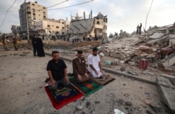 Palestinian Muslim men perform the morning Eid Al-Fitr prayer outdoors amid the destruction on the first day of the Muslim holiday which marks the end of the holy fasting month of Ramadan, following two days of Israeli airstrikes on Gaza, on May 13.