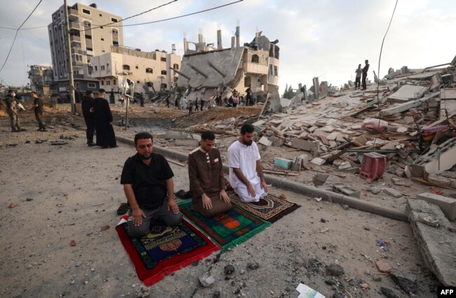 Warga muslim Palestina menjalankan salat Ied di sekitar puing-puing kerusakan akibat serangan udara Israel pada Hari Raya Idulfitri, 13 Mei 2021. (Foto: Mahmud Hams/AFP)