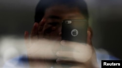 FILE - A man looks at his smartphone at a coffee shop in Phnom Penh, Cambodia, Oct. 23, 2018.