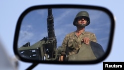 A Turkish soldier is reflected on a mirror as he stands guard on top of an armored personnel carrier on the Turkish-Syrian border near the Akcakale border crossing, October 4, 2012. 