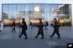 Chinese security guards march past an Apple store in Beijing, China, March 6, 2019.