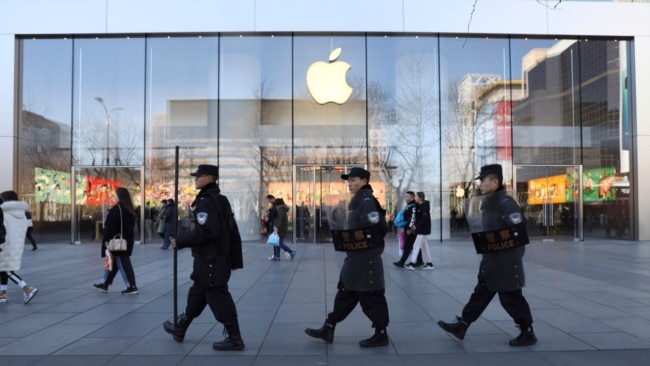 一队中国保安从北京一家苹果商店前走过。（2019年3月6日）