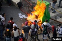 FILE - Demonstrators watch a barricade burn after clashes broke out while the Constituent Assembly election was being carried out in Caracas, Venezuela, July 30, 2017.