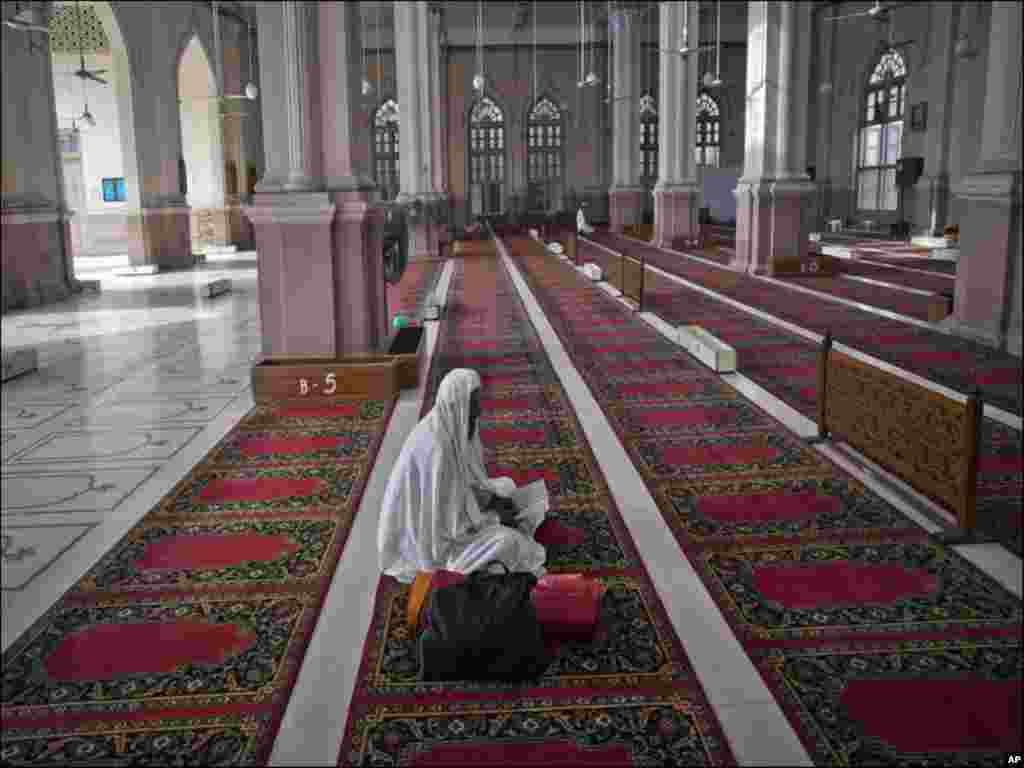 A man reads verses of the Koran on the second day of the holy month of Ramadan while sitting in the hall of Karachi&#39;s Memon Masjid.