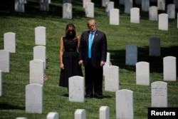 U.S. President Donald Trump and first lady Melania Trump stand among the graves during the annual "flags in" ceremonies before Memorial Day as the president visits Arlington National Cemetery in Arlington, May 23, 2019.