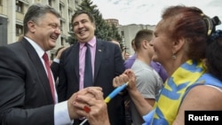 Ukrainian President Petro Poroshenko (L) and governor of Odessa region Mikheil Saakashvili (C) are greeted by a local resident near the regional state administration in Odessa, May 30, 2015.