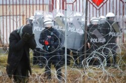 FILE - Polish servicemen spray tear gas during clashes with migrants and Polish border guards at the Belarus-Poland border near Grodno, Belarus, Nov. 16, 2021.