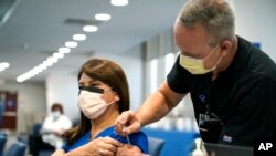 Registered nurse Alix Zacharski, left, receives a Pfizer COVID-19 booster shot from Douglas Houghton, right, at Jackson Memorial Hospital Tuesday, Oct. 5, 2021, in Miami. 