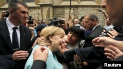 A woman tries to kiss German Chancellor Angela Merkel after she visited the Srebrenica exhibition in downtown of Sarajevo, Bosnia and Herzegovina, July 9, 2015.