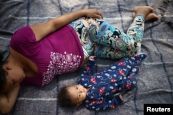 Aide and her baby son Clesner from Guatemala, rest after arriving with fellow Central American migrants, who are moving in a caravan through Mexico toward the U.S. border, at a shelter set up by the Catholic church, in Puebla, Mexico April 6, 2018.