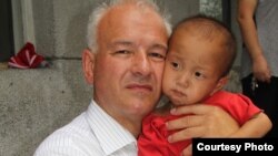 Ông Kim Hartzner bế một bé trai tại một viện mồ côi ở Haeju, Bắc Triều Tiên