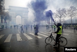 Protesters wearing yellow vests, a symbol of a French drivers' protest against higher diesel taxes, face off with French riot police during clashes at the Place de l'Etoile near the Arc de Triomphe in Paris, France, December 1, 2018.