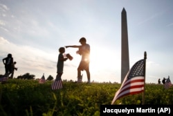 Rowan McManus, 10, directs his sister Fiona McManus, 5, as they help to remove 5,000 small U.S. flags representing suicides of active and veteran members of the military line the National Mall, Wednesday, Oct. 3, 2018.