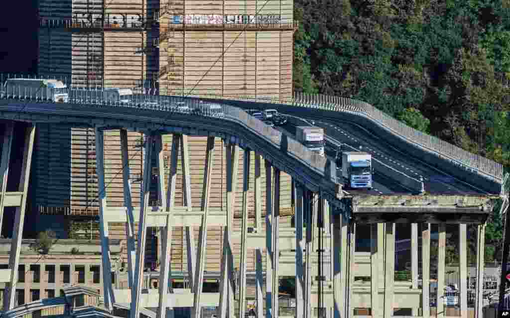 Cars and trucks are left on a section of the collapsed Morandi highway bridge in Genoa, northern Italy. A bridge on a main highway linking Italy with France collapsed in the Italian port city of Genoa during a sudden, violent storm, sending vehicles plunging 90 meters (nearly 300 feet) into a heap of rubble below.