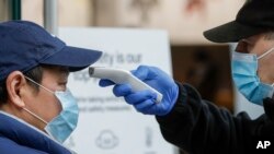 Seorang petugas keamanan mengukur suhu tubuh konsumen di kawasan perbelanjaan di Sydney, Australia, Minggu, 3 Januari 2021. (Foto: AP)